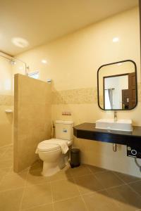 a bathroom with a toilet and a sink and a mirror at Rocco Hotel Bangsaen in Ban Laem Thaen