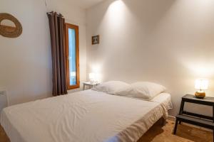 a bedroom with a white bed and a window at Le Refuge in Patrimonio
