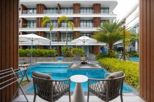 a swimming pool with chairs and tables and a building at Beachfront Luxury Apartment Bangtao Phuket in Bang Tao Beach