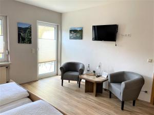 a bedroom with a desk and two chairs and a tv at Beilsteiner Gästehaus in Beilstein