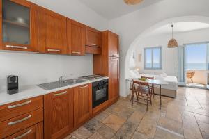 a kitchen with wooden cabinets and a table with a dining room at Sea view rooms in kardiani by TinosStay in Kardhianí