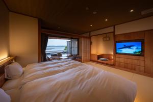 a bedroom with a large white bed and a flat screen tv at Hamabenoyado Kameya in Toba +77 photos