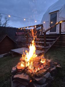 a fire pit in the yard in front of a rv at Glamping Ceahlau in Durău