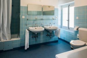 a blue tiled bathroom with two sinks and a toilet at Auberge aux 4 Vents in Fribourg +52 photos