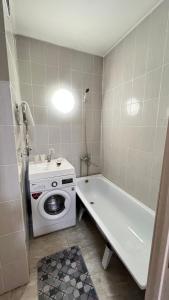 a bathroom with a washing machine and a bath tub at Daraboz in Almaty
