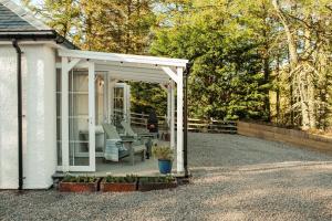 a white pergola with a chair on a patio at Blacksheep Cottage in Oban