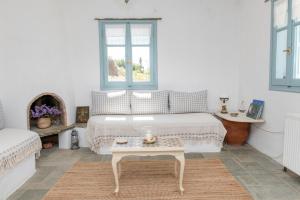 a white bedroom with a bed and a table at Αστραία - με θέα στο Αιγαίο in Agios Ioannis +21 photos