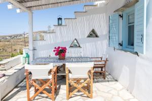 a patio with a table and chairs and a blue door at Αστραία - με θέα στο Αιγαίο in Agios Ioannis
