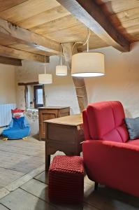 a living room with a red chair and a table at Gîte Escapade À La Voreille in Mazirat