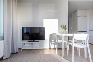a white dining room with a table and a tv at Spot Apartments Oulu in Oulu +9 photos