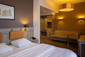 ein Hotelzimmer mit einem Bett und einer Couch in der Unterkunft Blanckthys Hotel Voeren in Voeren