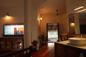 a bathroom with a sink and a flat screen tv at Panackal Heritage Home in Trivandrum