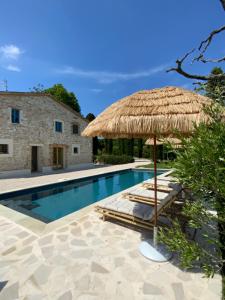 a swimming pool with a straw umbrella and lounge chairs at Monte Pino in Pergola