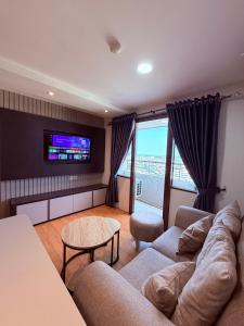 a living room with a couch and a tv at SkyBreeze Sentraland in Medan