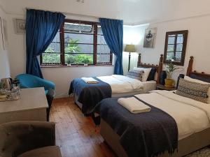 a bedroom with two beds and a table and a window at John Bauer Pottery Studio in Cape Town