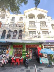 a white building with red tables and chairs in front of it at SOLÉRA 2 Homestay in Phú Quốc