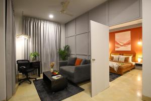 a living room with a couch and a bed at Studio Serviced Apartments near Fortis Hospital in Gurgaon