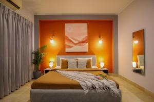 a bedroom with a bed with an orange wall at Studio Serviced Apartments near Fortis Hospital in Gurgaon +32 photos