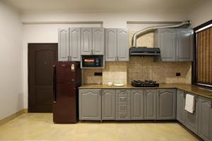 a kitchen with gray cabinets and a brown refrigerator at Studio Serviced Apartments near Fortis Hospital in Gurgaon