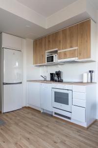 an empty kitchen with white appliances and wooden cabinets at Spot Apartments Oulu in Oulu