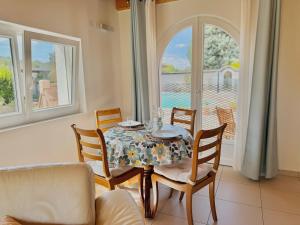 a dining room with a table and chairs and a window at Charmante maisonnette avec piscine partagée in Charancieu