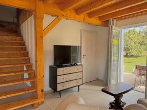 a living room with a television and a staircase at Charmante maisonnette avec piscine partagée in Charancieu