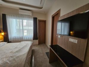 a hotel room with a bed and a flat screen tv at Hotel LimeStarow in Bijni