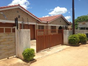 a house with a wooden gate in front of it at Hardrock Guest House in Francistown