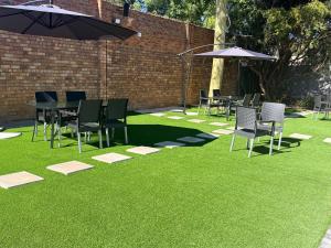 a lawn with chairs and tables and umbrellas at Rugira Guest House in Vosburg