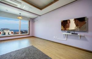 an empty living room with a tv on a wall at Pension Ora in Samcheok