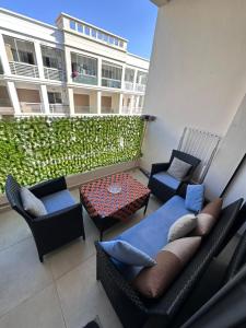a patio with couches and a table and chairs at Studio Luxe Bouznika Beach Piscine, Clim, Wi-Fi ,Check in 24h Plage 5 min in Bouznika