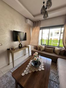 a living room with a couch and a table at Studio Luxe Bouznika Beach Piscine, Clim, Wi-Fi ,Check in 24h Plage 5 min in Bouznika