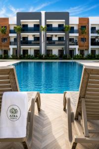 a swimming pool with two chairs and a building at Azra Mila Appart luxe famille uniquement in Saïdia