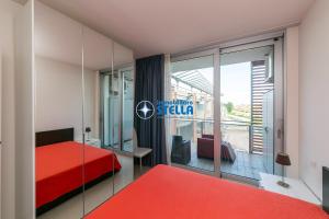 a bedroom with a red bed and a large window at Condominio Mimose in Eraclea Mare