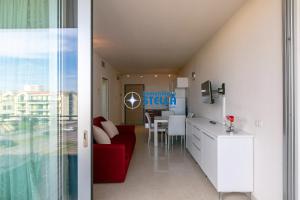 a living room and a kitchen with a red couch at Condominio Mimose in Eraclea Mare
