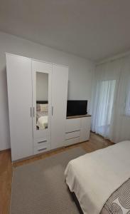a white bedroom with a bed and a tv at Una Vibe Studio in Bosanska Krupa
