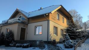 una casa en la nieve con un árbol delante en Achilla Bed & Breakfast, en Český Krumlov