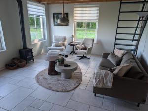 a living room with a couch and chairs and a staircase at De Dagloner in Nieuwlande