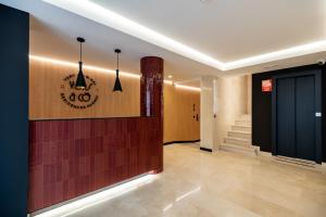 a lobby with a staircase and a clock on the wall at VORS&Co Jerez in Jerez de la Frontera