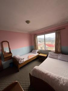 a hotel room with two beds and a window at Subhechchha Hotel in Charikot