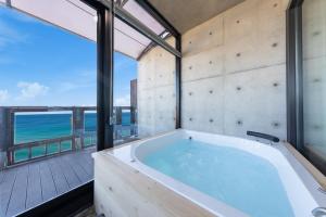 a bath tub in a room with a view of the ocean at Goseong Romiet Pension in Goseong