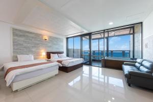 a bedroom with two beds and a couch and windows at Goseong Romiet Pension in Goseong