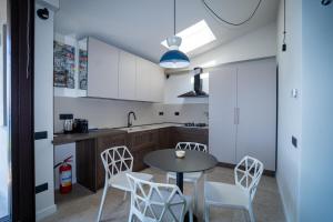a kitchen with a table and white chairs at Lagò-Anguillara Sabazia in Anguillara Sabazia