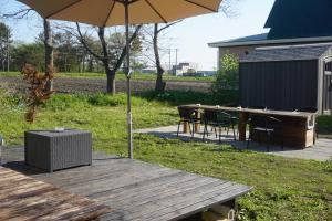 a table and chairs with an umbrella on a deck at Kaede Lakehouse Toya in Lake Toya