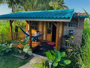 two people sitting in a hammock in a tiny house at Tetebatu Sasak House Bungalow in Tetebatu
