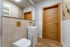 a bathroom with a toilet and a wooden door at Gościniec in Sopot
