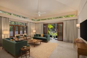a living room with green furniture and large windows at Oasis County Villas in Bangalore