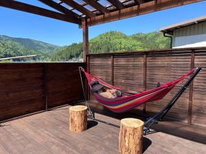 a man sleeping in a hammock on a deck at Nagomi Yado Origin in Ayabe
