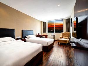 a hotel room with two beds and a chair at 弗克斯酒店 in Zunyi