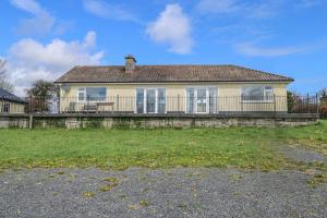 a yellow house with a fence in front of a yard at Sweetbriar Lodge in Castlerea